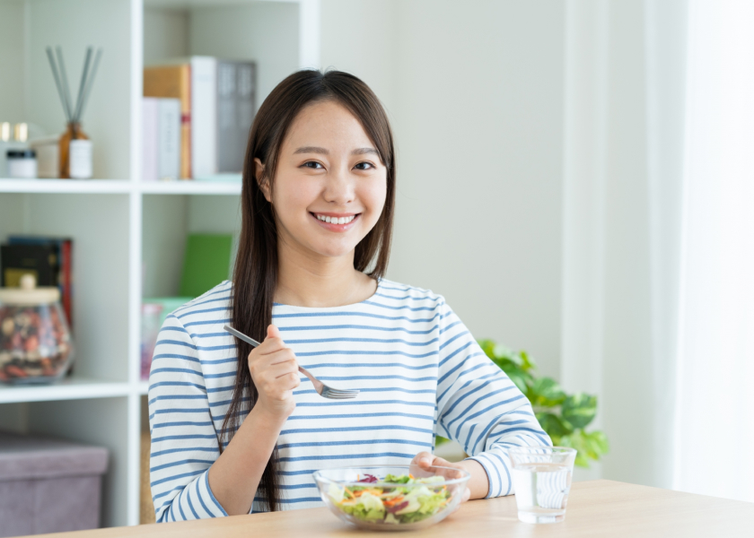 画像：サラダを前に笑顔の女性